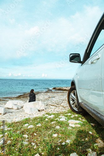 woman sitting at rock near suv car at seaside enjoying the view © phpetrunina14