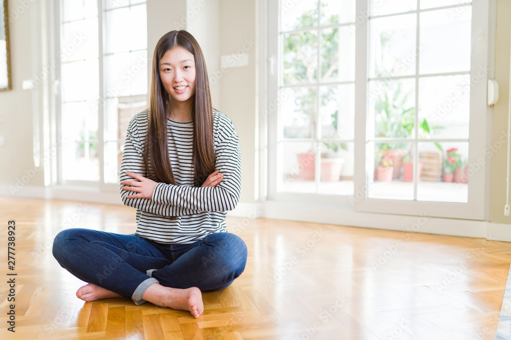 Beautiful Asian woman sitting barefoot on the floor at home happy face smiling with crossed arms looking at the camera. Positive person. Beautiful Asian woman sitting barefoot on the floor at home happy face smiling with crossed arms looking at the camera. Positive person.