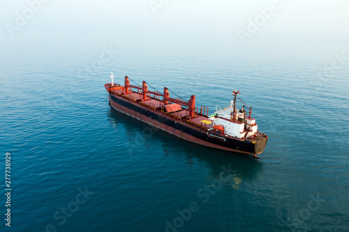 Aerial view of high-speed sea vessel for transportation of a cargo vessel at high speed is drifting near the seaport of the city at sunset. Ship on the background of blue sea water. Import, export