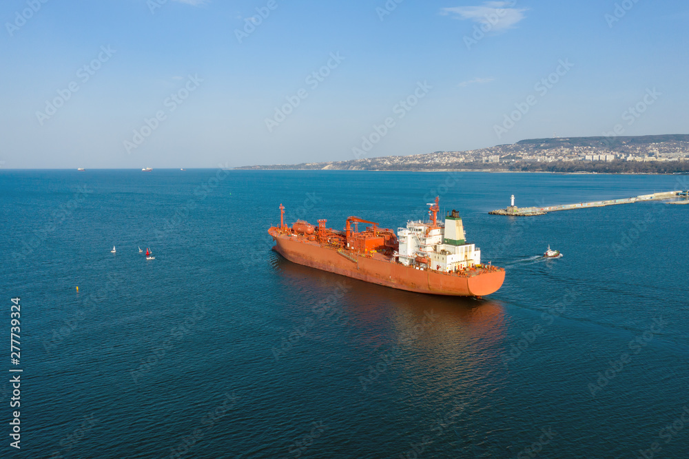 Aerial view of sea vessel for transportation of a cargo vessel at high speed is drifting near the seaport of the city at sunset. Ship on the background of blue sea water. Import, export 
