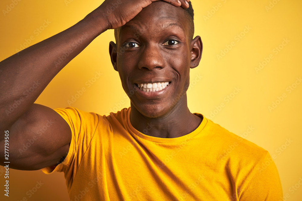 African american man wearing casual t-shirt standing over isolated yellow background stressed with hand on head, shocked with shame and surprise face, angry and frustrated. Fear and upset for mistake. African american man wearing casual t-shirt standing over isolated yellow background stressed with hand on head, shocked with shame and surprise face, angry and frustrated. Fear and upset for mistake.
