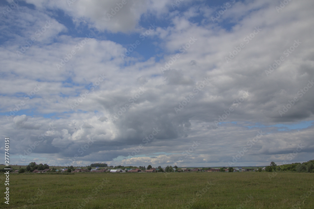 summer landscape with a view of the village under a blue sky and white clouds in Chuvashia
