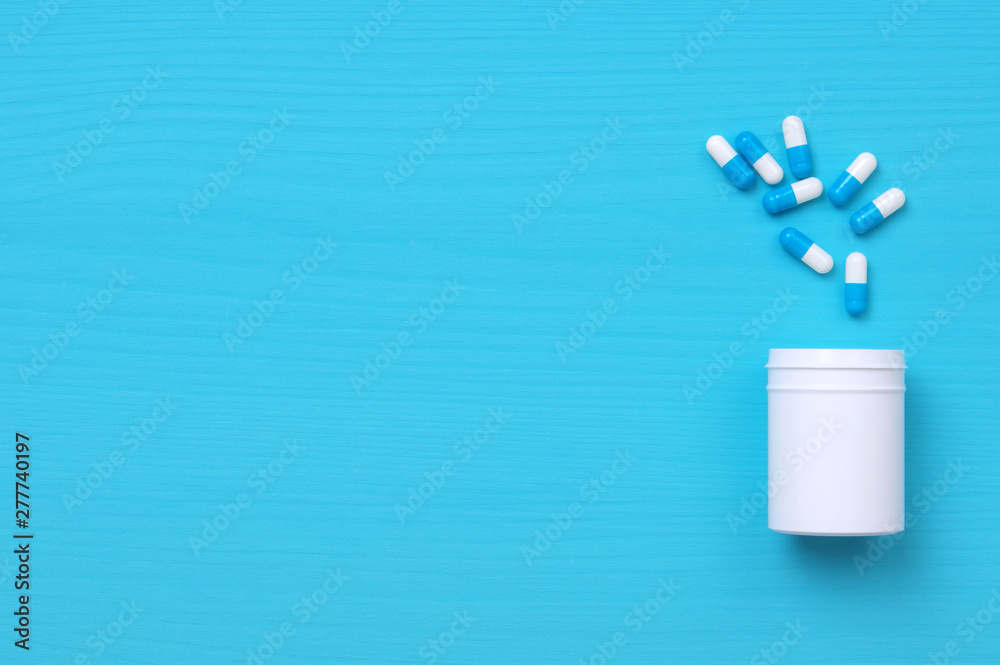Pills and white bottle on blue background. Pills and white bottle on blue background.