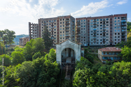 Old rusty and functioning ropeway or cable car cabins in Chiatura. Panorama of the city district and apartment buildings on the rock and Upper cable car station Perevisa.