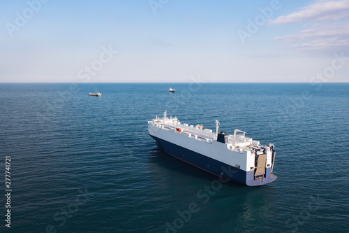 Aerial view of high-speed sea vessel for transportation of cargo vessel at high speed is drifting near the seaport of the city at sunset. Ship on the background of blue sea water. Import, export. Top