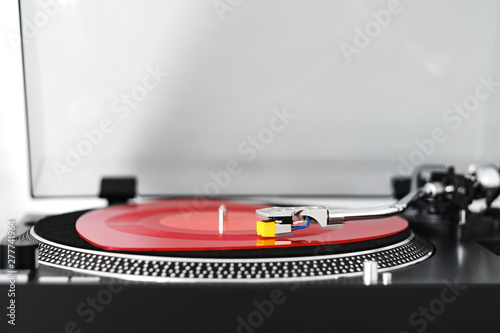 Side view of a vinyl turntable with a red heart-shaped vinyl record with a needle, on a white background close-up. Stylus with a needle on a DJ vinyl player. Valentine's Day. Love symbol