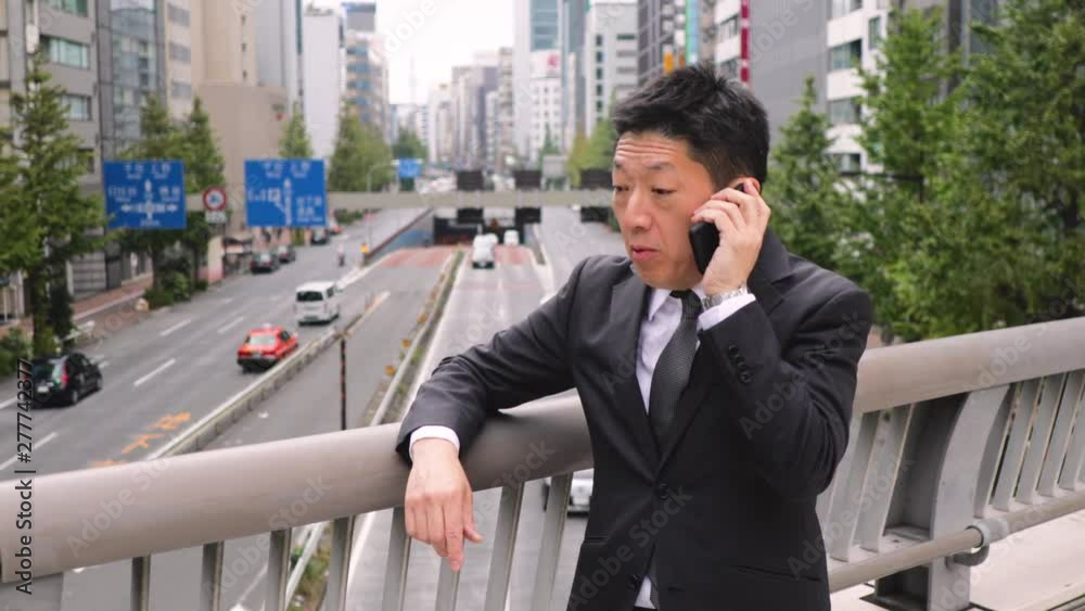 Japanese businessman talking on a cell phone. Japanese businessman talking on a cell phone.