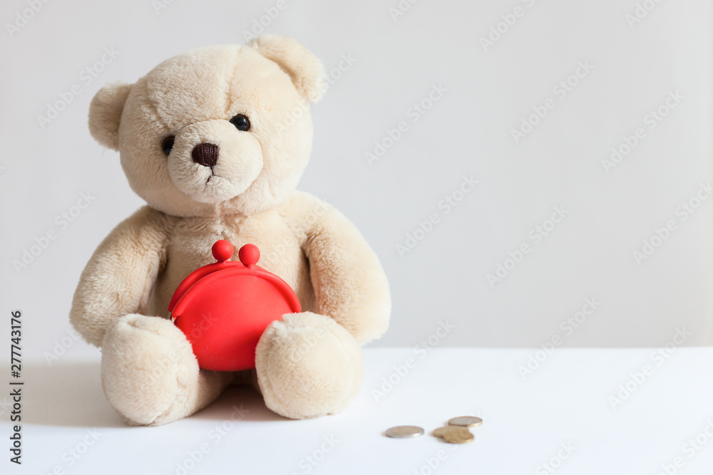 Teddy bear with red wallet, coins,dollars. Business and finance concept/ Financial support, business, family, alimony, maintenance, charity, investing in children concept Teddy bear with red wallet, coins,dollars. Business and finance concept/ Financial support, business, family, alimony, maintenance, charity, investing in children concept