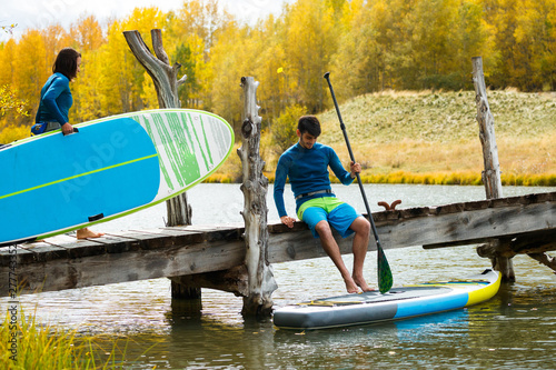 A man and a woman prepare their inflatable stand up paddle boards for SUPing in an alpine lake in the San Juan Mountains, Colorado in autumn. photo