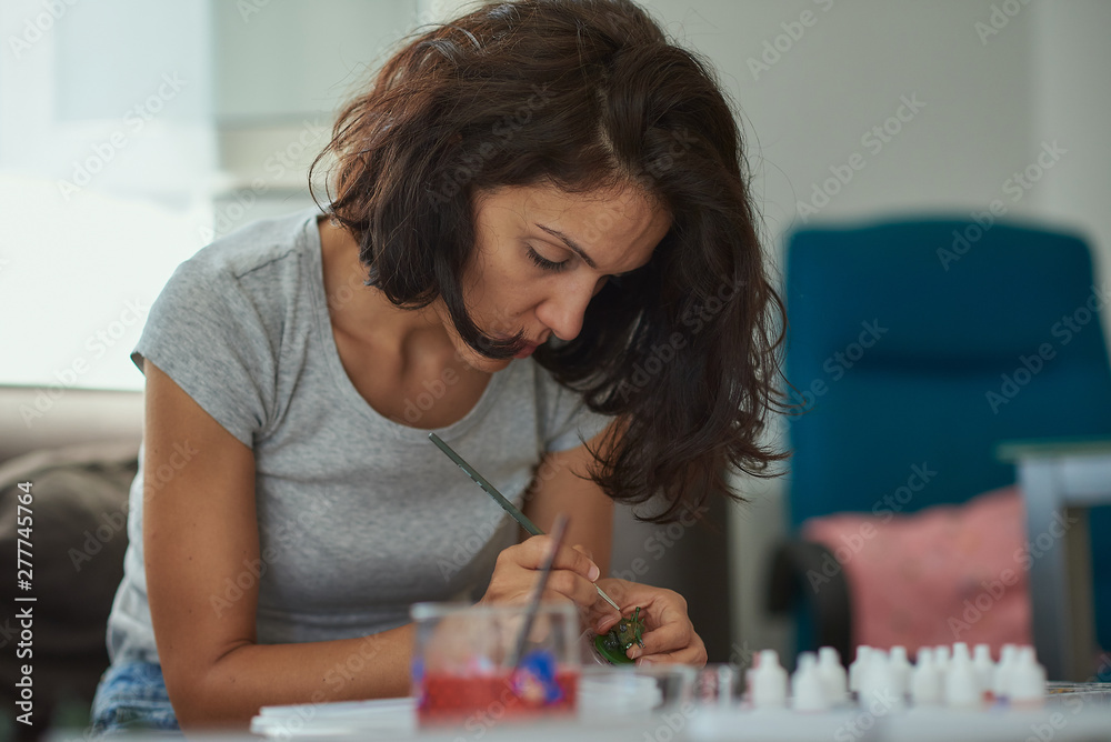 Brunette woman of latin race painting small figures with a white background. Brunette woman of latin race painting small figures with a white background.