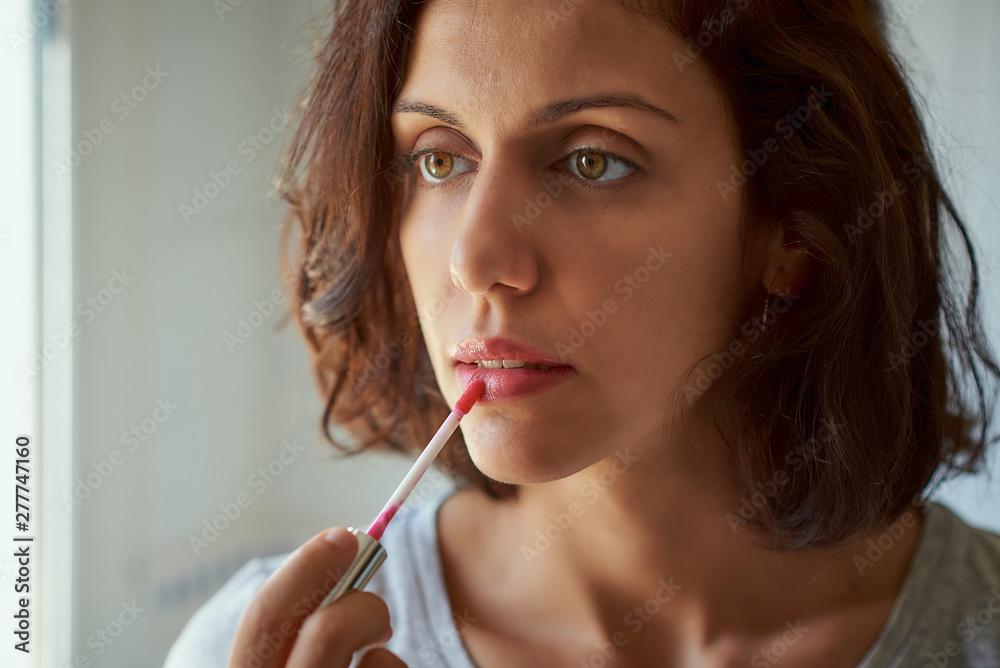 Brunette woman of latin race doing makeup in a mirror. Brunette woman of latin race doing makeup in a mirror.