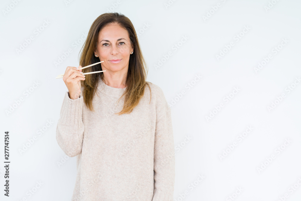 Middle age woman holding asian chopsticks over isolated background with a confident expression on smart face thinking serious Middle age woman holding asian chopsticks over isolated background with a confident expression on smart face thinking serious