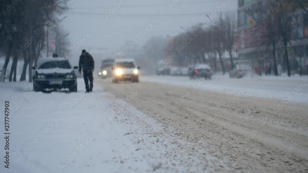 Car urban traffic in the heavy snowstorm blizzard snowfall on the snowy road in the winter city 