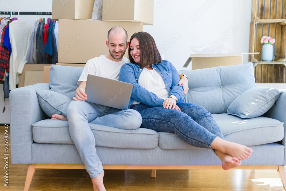 Young couple sitting on the sofa at new home using computer laptop, smiling happy for moving to a new apartment Young couple sitting on the sofa at new home using computer laptop, smiling happy for moving to a new apartment