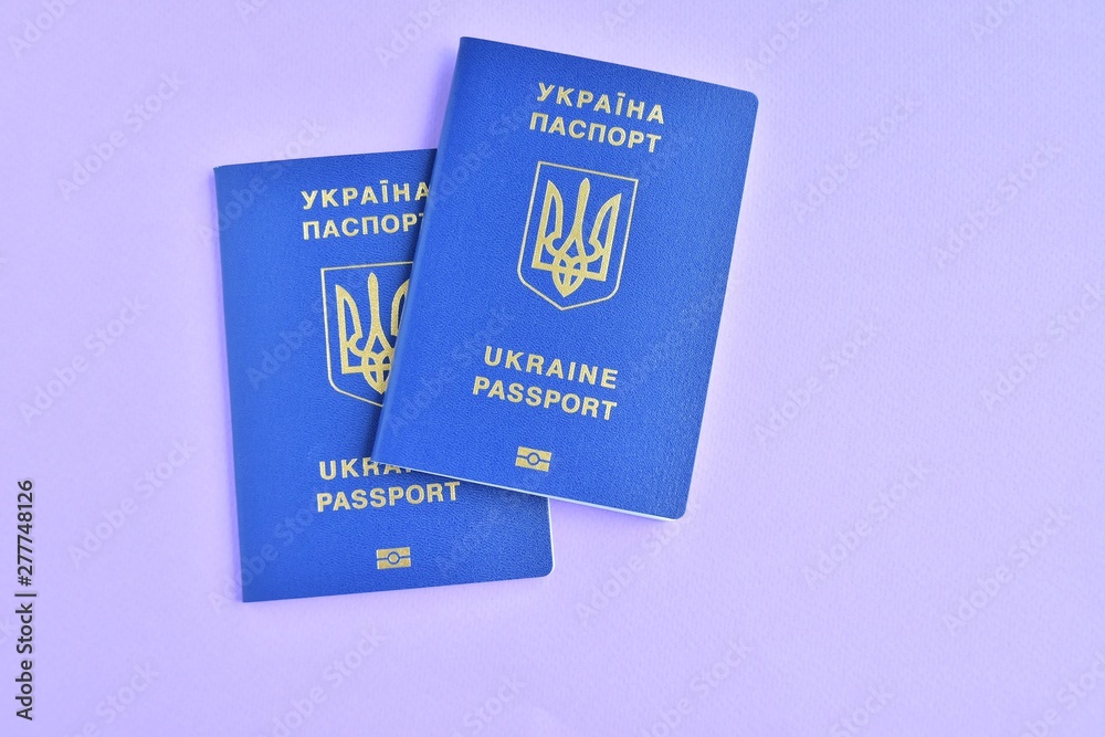 Two Biomedical Ukraine id passports on violet background with selective focus and empty space for photo or text. Ukrainian id passport with a golden symbol trident on neon backdrop. Copy space Two Biomedical Ukraine id passports on violet background with selective focus and empty space for photo or text. Ukrainian id passport with a golden symbol trident on neon backdrop. Copy space