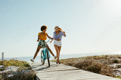 Two women having fun with a bicycle at beach