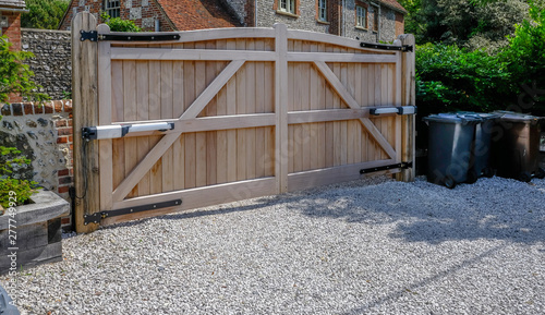 Large wooden entry electric gates with stone driveway. photo