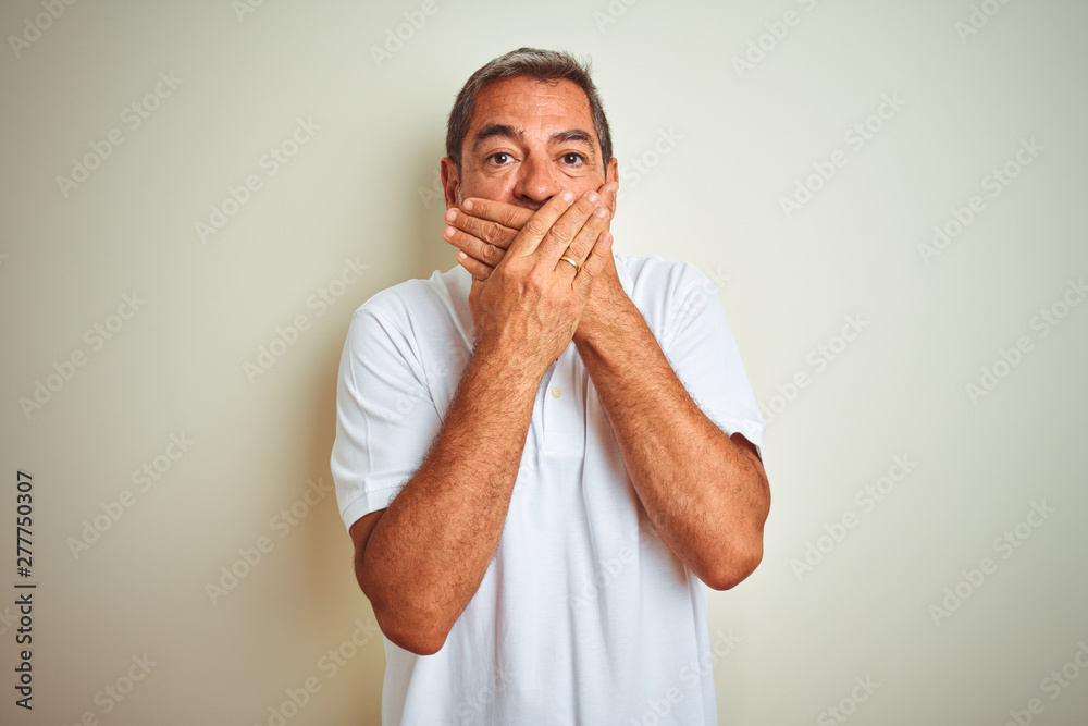 Handsome middle age man wearing polo standing over isolated white background shocked covering mouth with hands for mistake. Secret concept. Handsome middle age man wearing polo standing over isolated white background shocked covering mouth with hands for mistake. Secret concept.