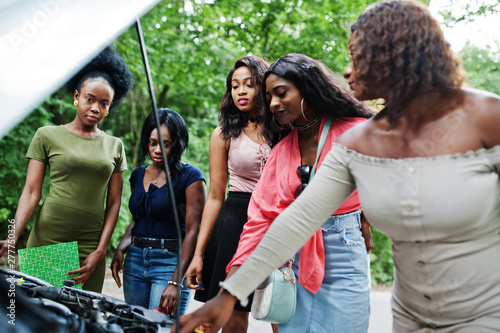 Group of five african american traveler girls looking at broken car open hood.