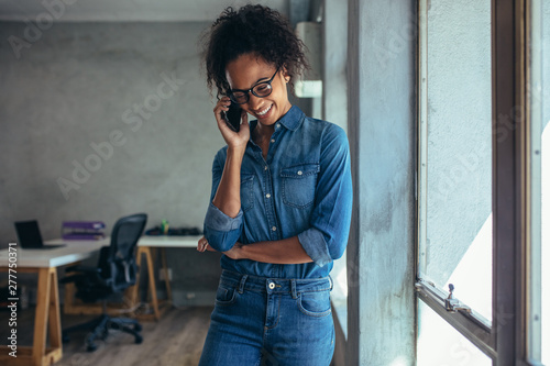 Positive woman in office talking on phone