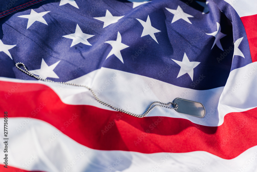 Silver badge on chain near American flag with stars and stripes Silver badge on chain near American flag with stars and stripes