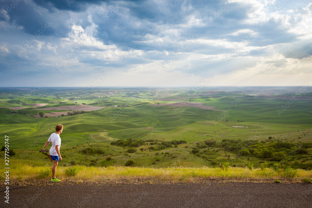 Distance runner stretching during a late afternoon run on the scenic windy road up Steptoe Butte State Park in eastern Washington state in peak spring conditions. Distance runner stretching during a late afternoon run on the scenic windy road up Steptoe Butte State Park in eastern Washington state in peak spring conditions.