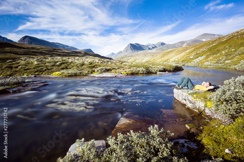 Rondane National Park, Norway: A male hiker by the river that flows from the Rondvassbu lodge towards Otta and comes by the parking in Spranget. photo