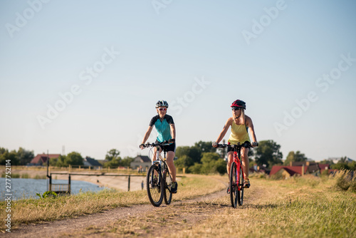 Women on bike riding by the lake shore outdoors at the park