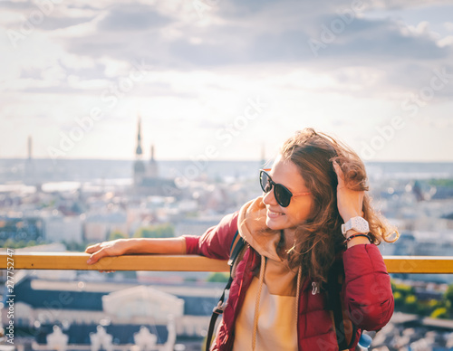 Young beautiful happy girl traveler on the viewing platform against the background of the old town of Riga, Latvia, travel to the Baltic countries