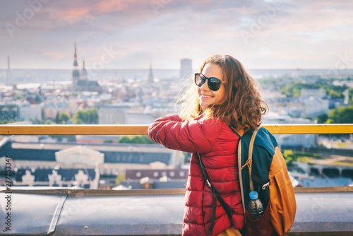 Young beautiful happy girl traveler on the viewing platform against the background of the old town of Riga, Latvia, travel to the Baltic countries
