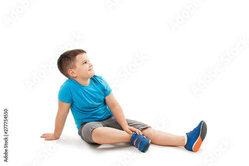 Portrait of a cute little boy sitting on the floor, looking up. Isolated on white background 