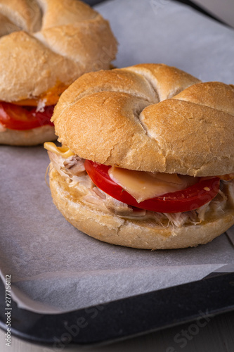 Two homemade burger Vienna Kaiser bread bun bread roll with chicken meat tomato mustard mayonnaise on baking tray sheet parchment paper white background photo