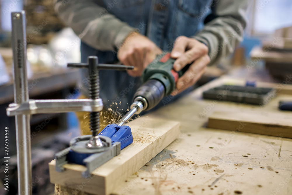 Woodwork and furniture making concept. Caucasain man carpenter installs the furniture hinge. Pocket hole joinery concept.