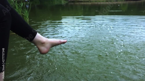 The girl sits on the platform and splashes water feet