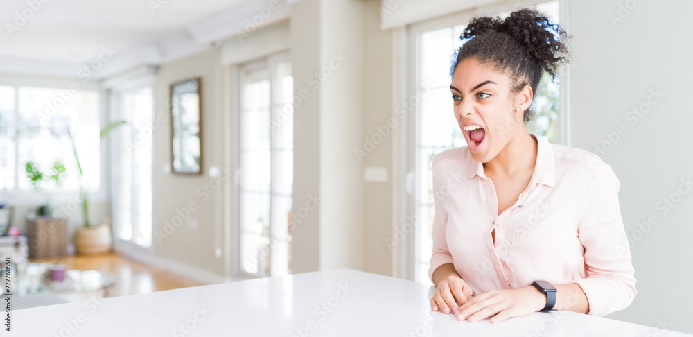 Wide angle of beautiful african american woman with afro hair angry and mad screaming frustrated and furious, shouting with anger. Rage and aggressive concept. Wide angle of beautiful african american woman with afro hair angry and mad screaming frustrated and furious, shouting with anger. Rage and aggressive concept.