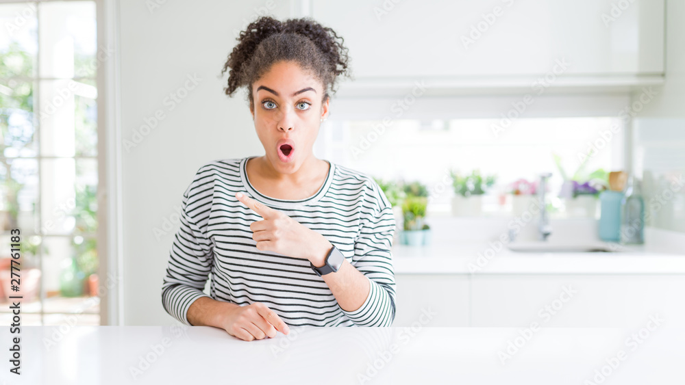 Beautiful african american woman with afro hair wearing casual striped sweater Surprised pointing with finger to the side, open mouth amazed expression. Beautiful african american woman with afro hair wearing casual striped sweater Surprised pointing with finger to the side, open mouth amazed expression.