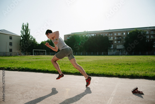 Low section shot of male athlete starting a race in stadium with sunflare.