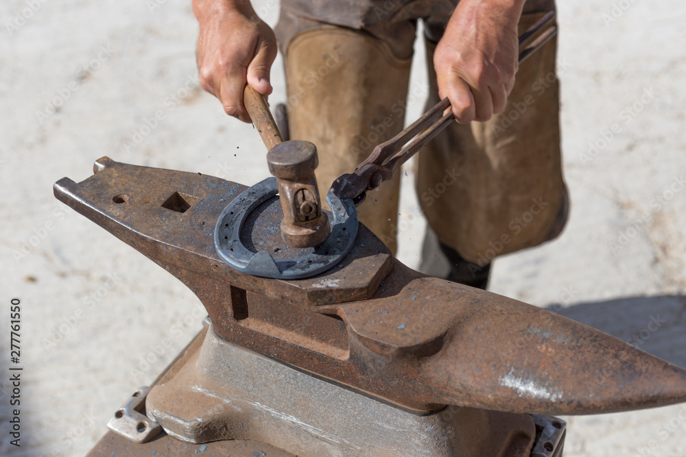 Farrier hammers a hot horseshoe on anvil Farrier hammers a hot horseshoe on anvil