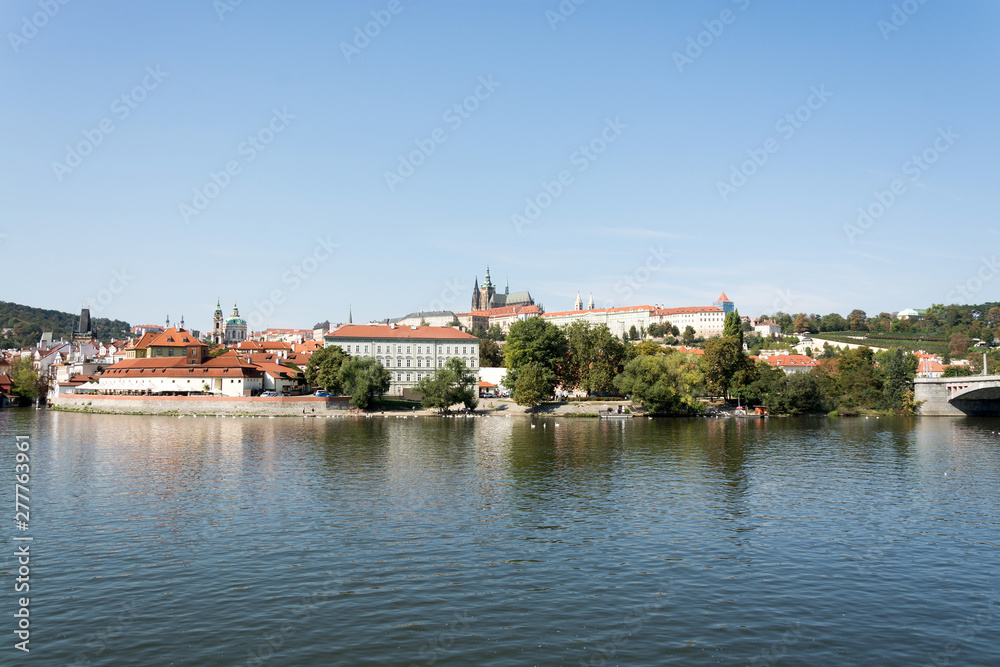 Panoramic view of Vltava river, Prague castle, and colorful rooftops of New Town on a bright summer day, in Prague, Czech Republic