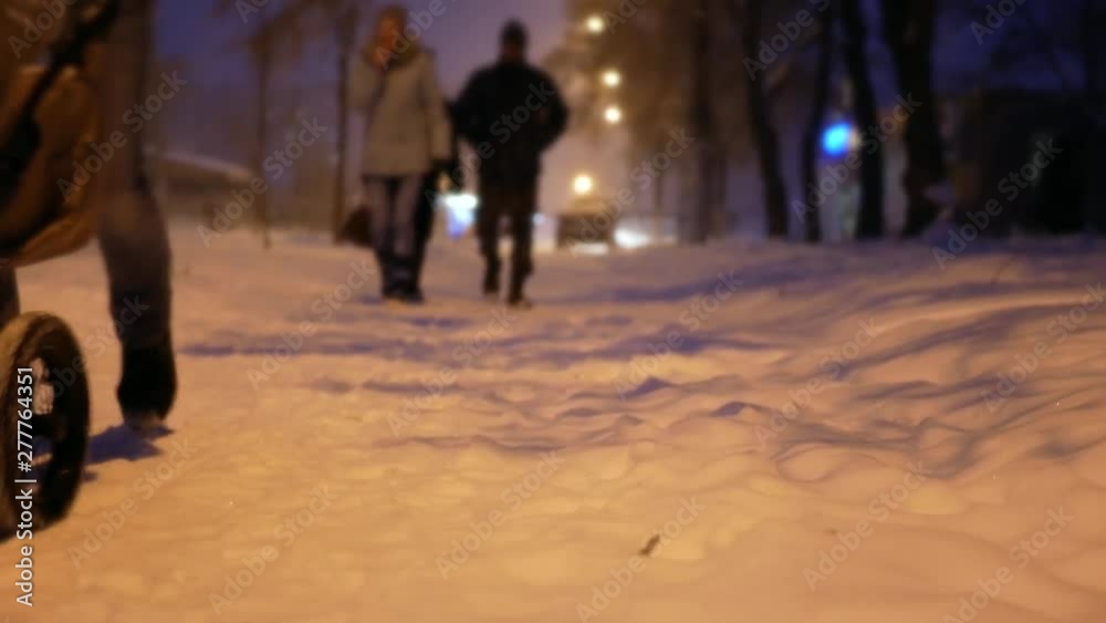 Snowy winter weather and people in the snowfall blizzard in the street lights of evening night city Snowy winter weather and people in the snowfall blizzard in the street lights of evening night city