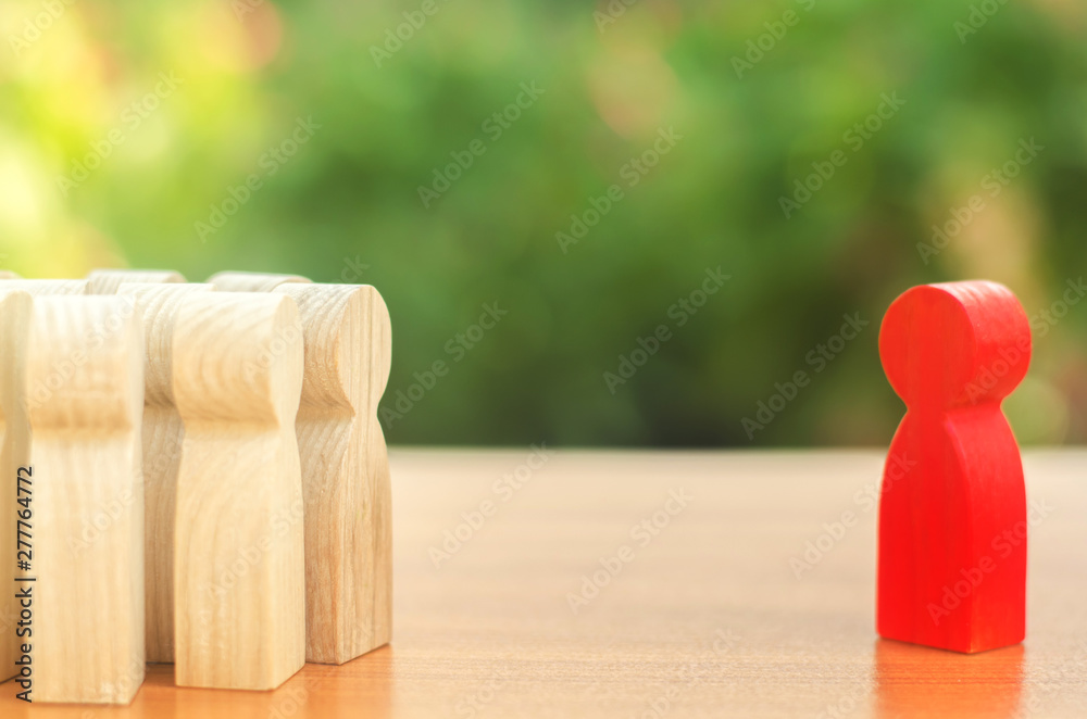 Red figurine of a man stands aside from the crowd of people. Asociality, sociopathy. Rejected from society, lonely. Infected, fear and misunderstanding. Development of leadership and social qualities.