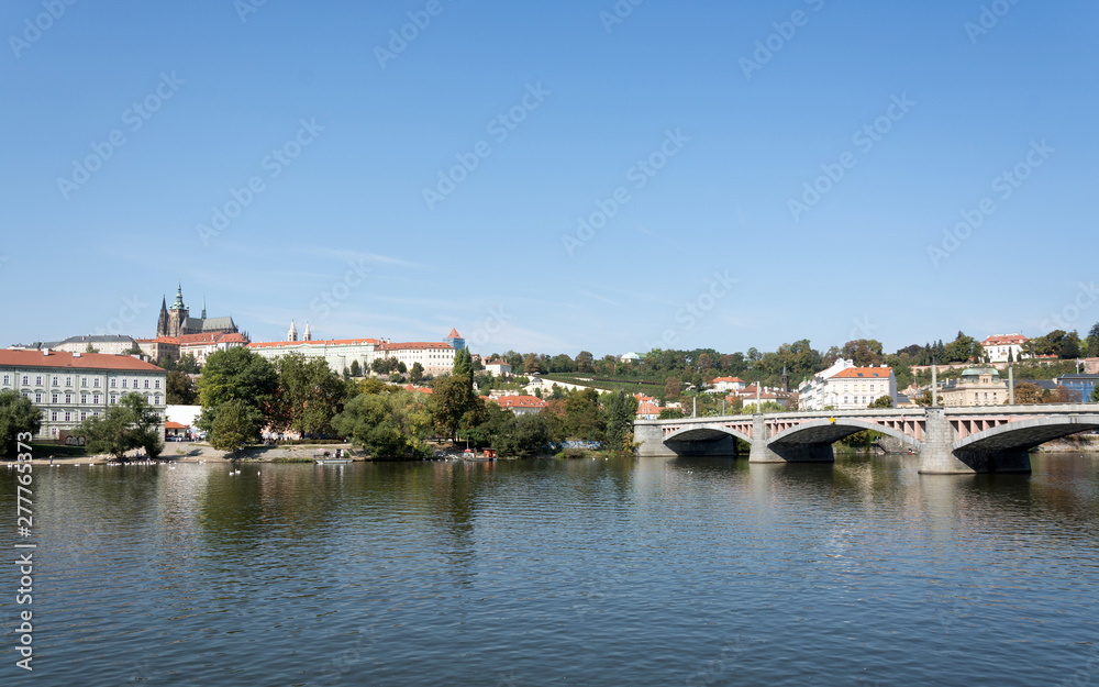 Panoramic view of Vltava river, Prague castle, and colorful rooftops of New Town on a bright summer day, in Prague, Czech Republic