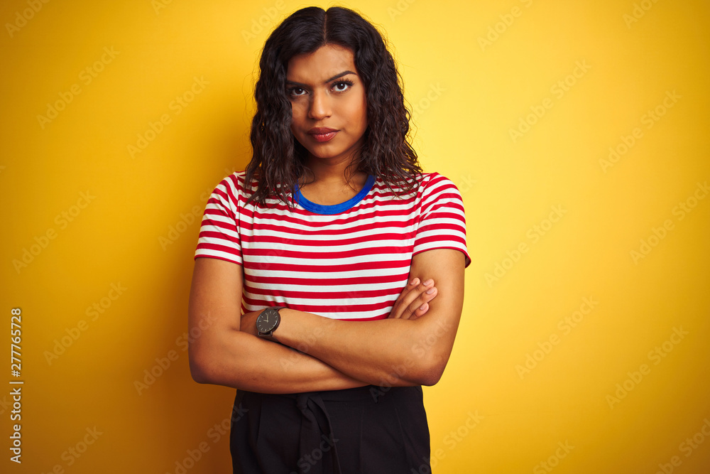 Obraz premium Transsexual transgender woman wearing stiped t-shirt over isolated yellow background skeptic and nervous, disapproving expression on face with crossed arms. Negative person.