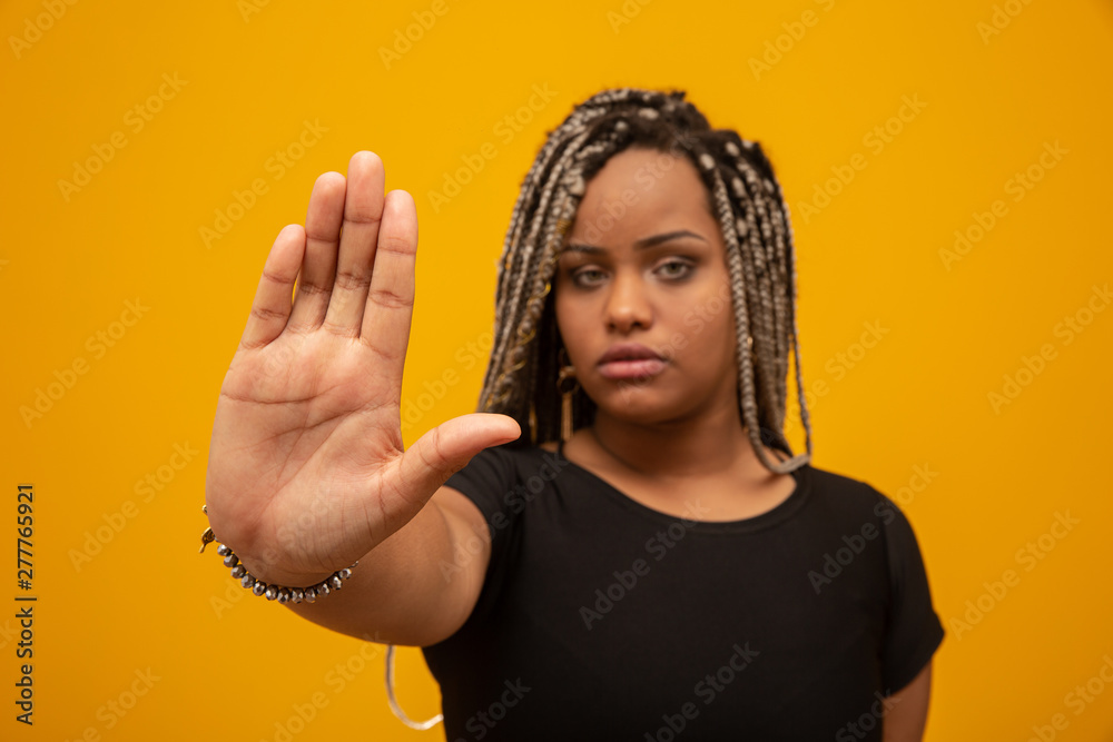 Obraz premium Young African American woman shown hand on sign for them to stop with racial prejudice.