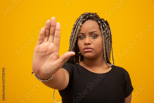 Young African American woman shown hand on sign for them to stop with racial prejudice. photo