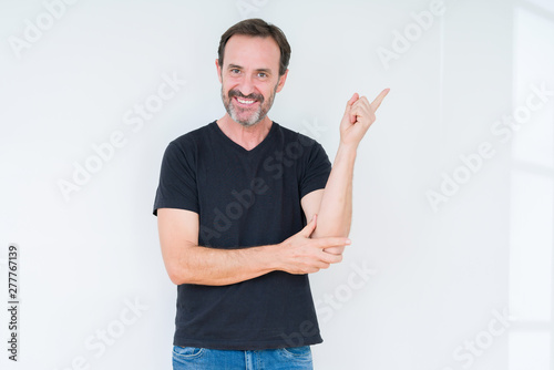 Senior man over isolated background with a big smile on face, pointing with hand and finger to the side looking at the camera.