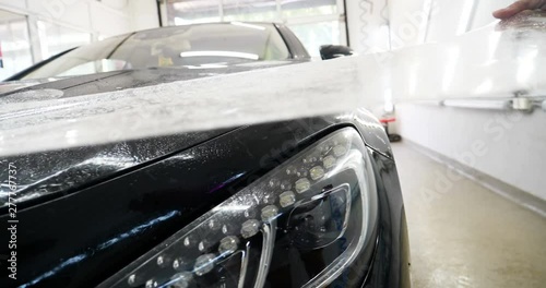 Close up to PPF installation process on a front headlight and hood. PPF is a Paint Protection Film which protect paint from scratches and stone chips. Concept of: Guard, Protect, Car, New, Work.