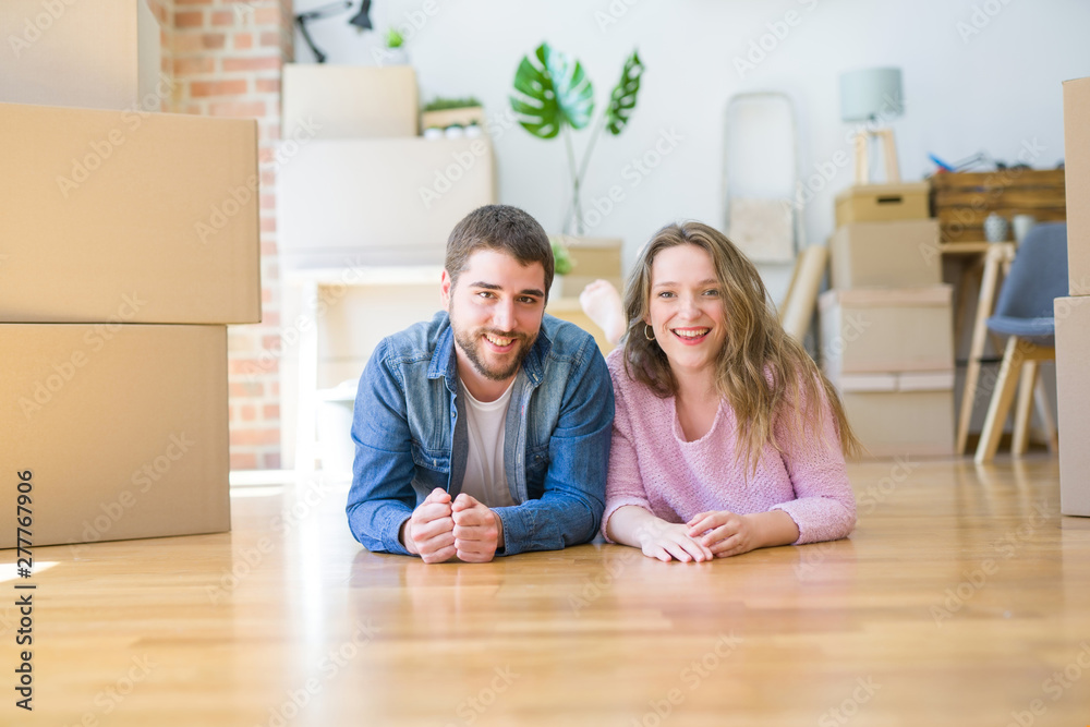 Young beautiful couple in love relaxing lying on the floor together with cardboard boxes around for moving to a new house Young beautiful couple in love relaxing lying on the floor together with cardboard boxes around for moving to a new house