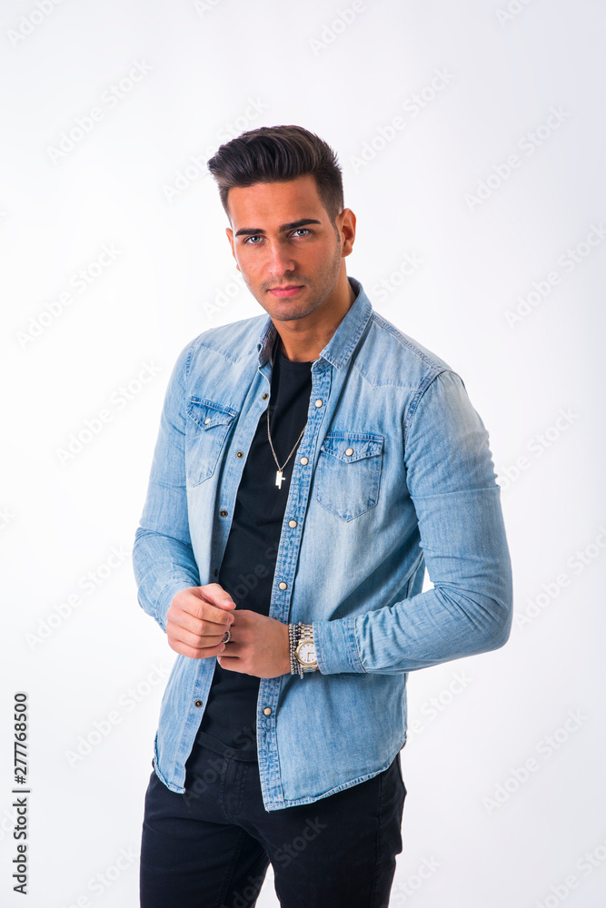Young handsome man standing in studio shot, on white, wearing denim shirt and black jeans Young handsome man standing in studio shot, on white, wearing denim shirt and black jeans