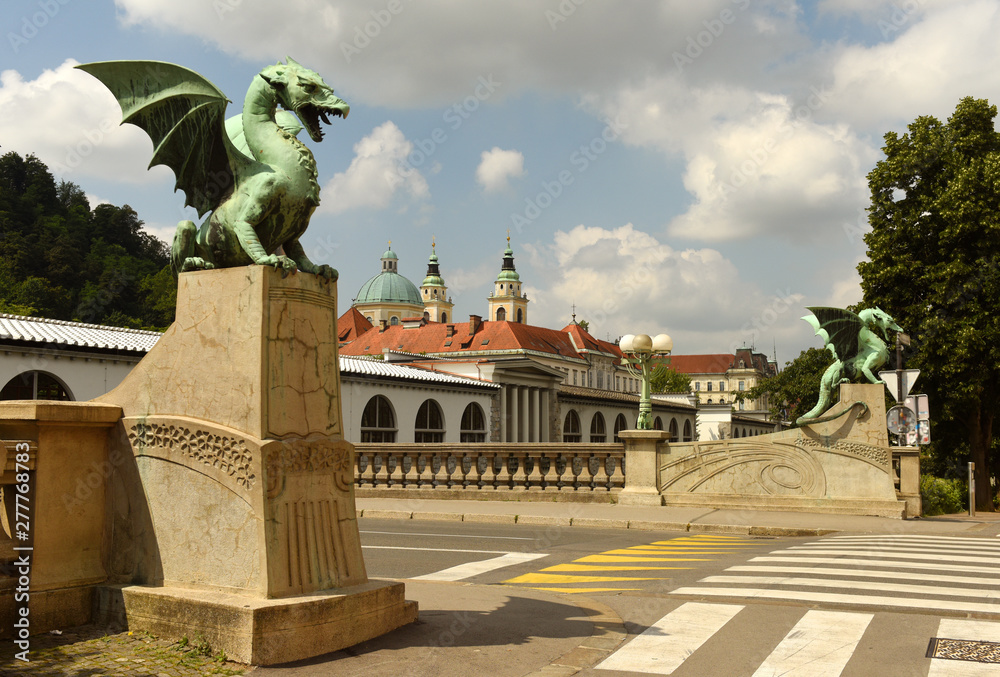 The Dragon Bridge, adorned with famous dragon statues and Cathedral of St. Nicholas at the background in Ljubljana, Slovenia